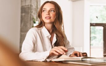 young woman sitting at her home desk with laptop in front of her - she looks independent and successful