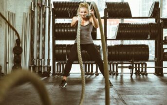a blonde woman working out in a gym with large ropes