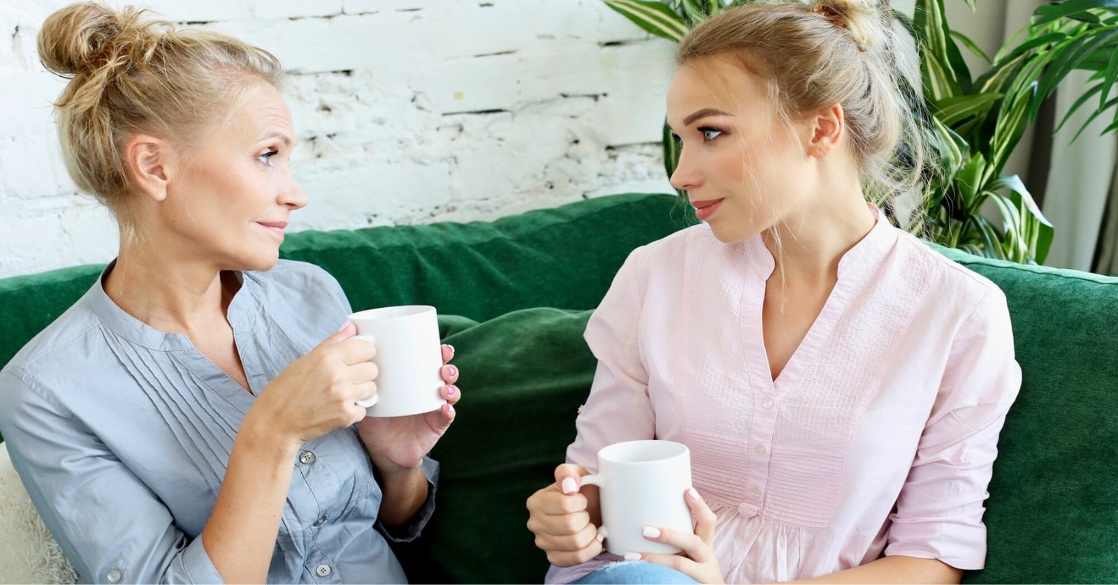 mother giving her grown daughter some unsolicited advice while they book drink hot drinks at home