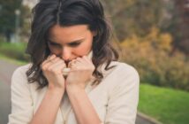woman looking regretful with her hands near her face and her head down
