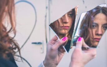 woman looking into two shards of a mirror thinking she is ugly