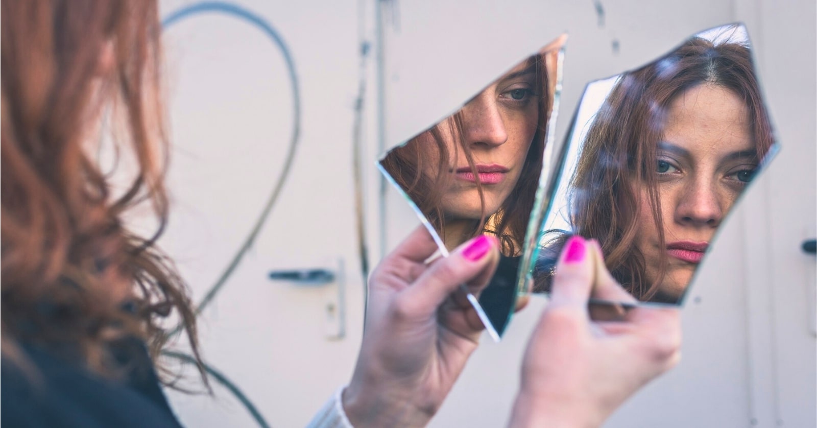 woman looking into two shards of a mirror thinking she is ugly