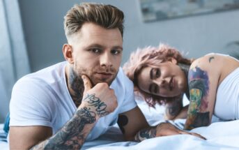 tattooed couple laying in bed