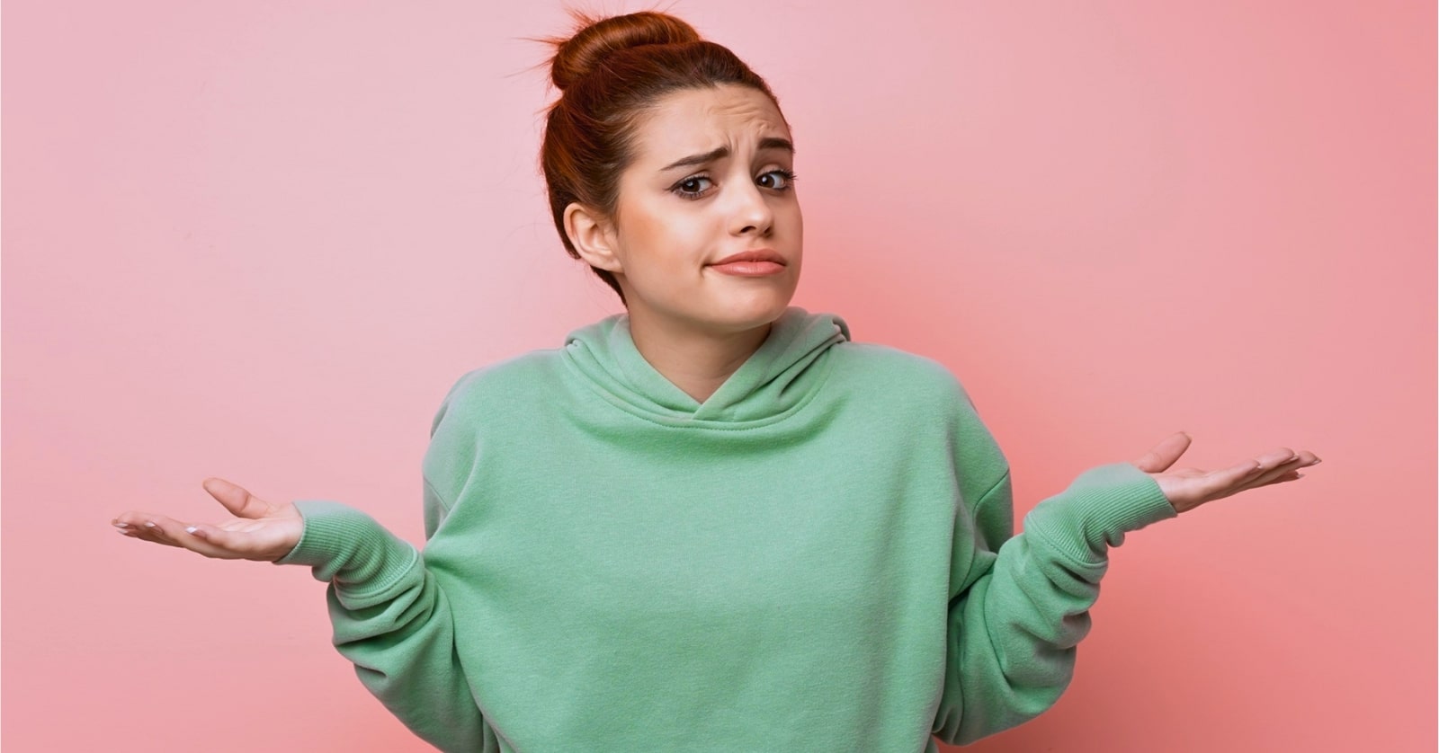 young woman in green hoodie shrugging her shoulders as if to say "I don't know"