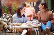 two classy ladies having a conversation at a table in a garden center cafe, they are smiling and enjoying themselves