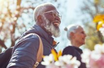 happy senior black man and white lady walk among the spring blooms in their local park