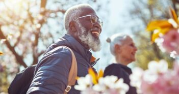 happy senior black man and white lady walk among the spring blooms in their local park