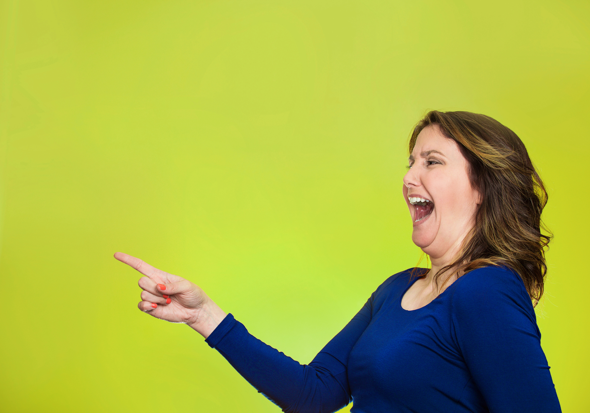 A woman with long brown hair, wearing a blue shirt, is laughing and pointing to the left of the image. She is set against a bright yellow-green background.