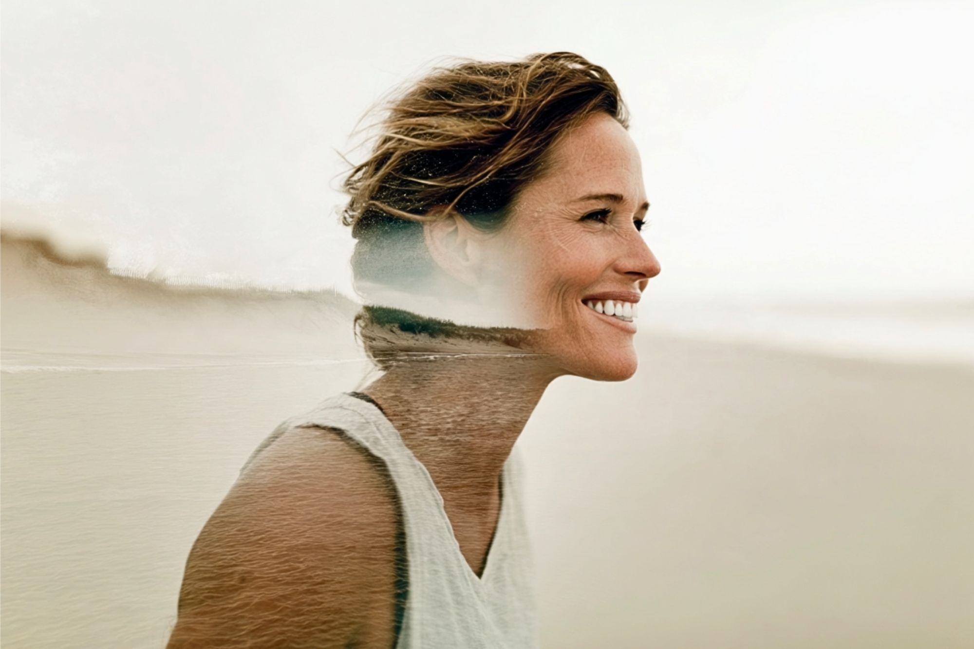 A smiling woman with short brown hair stands outdoors, overlaid with a double exposure effect of a serene beach scene.