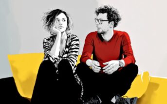 A woman and a man sit on a yellow couch. The woman, wearing a striped shirt, rests her chin on her hand and looks away thoughtfully. The man in a red shirt and glasses looks at her, speaking animatedly.