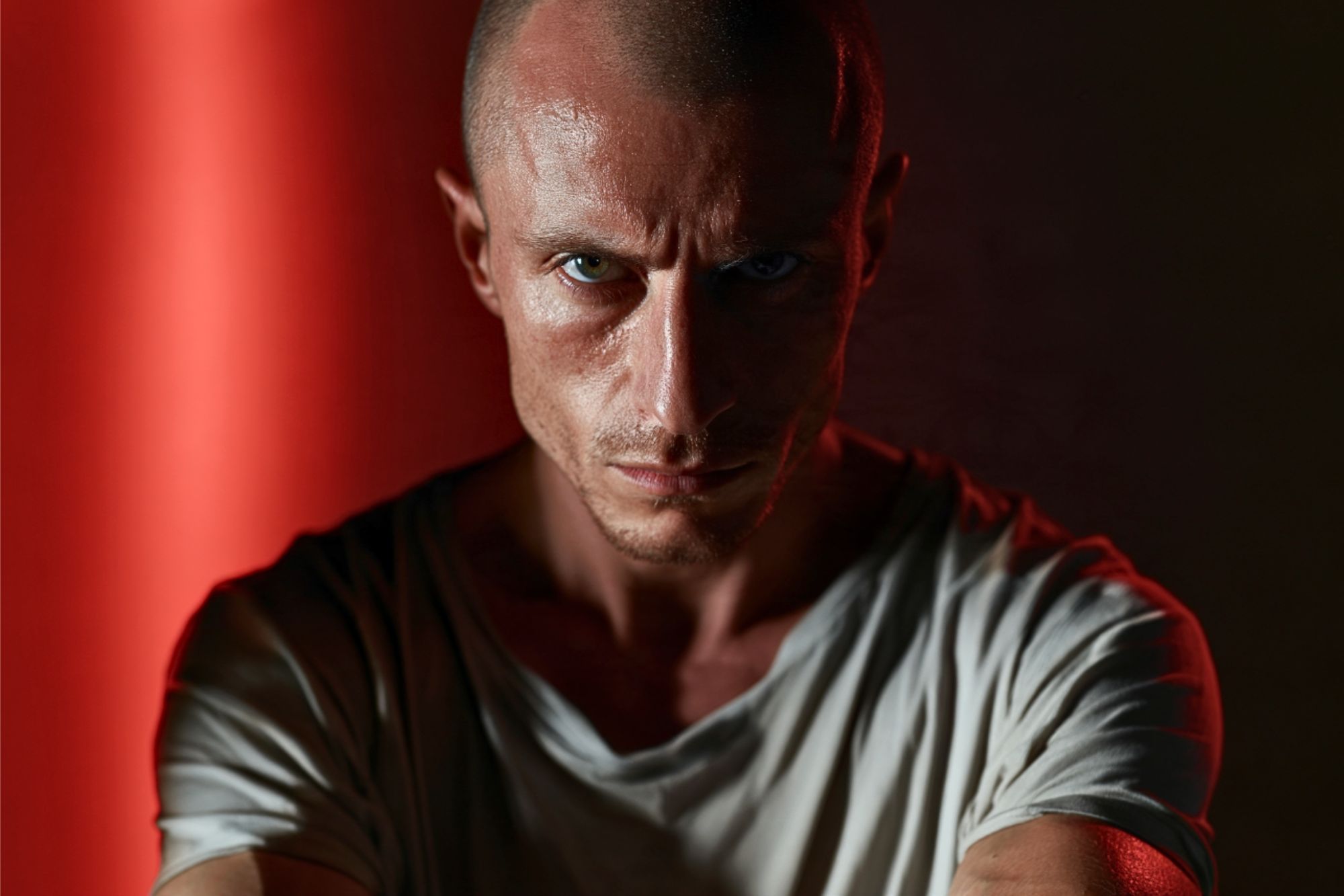 Close-up portrait of a man with a shaved head and intense gaze.