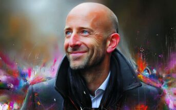 Portrait of a smiling bald man with a beard, wearing a coat and scarf against an abstract, colorful background.