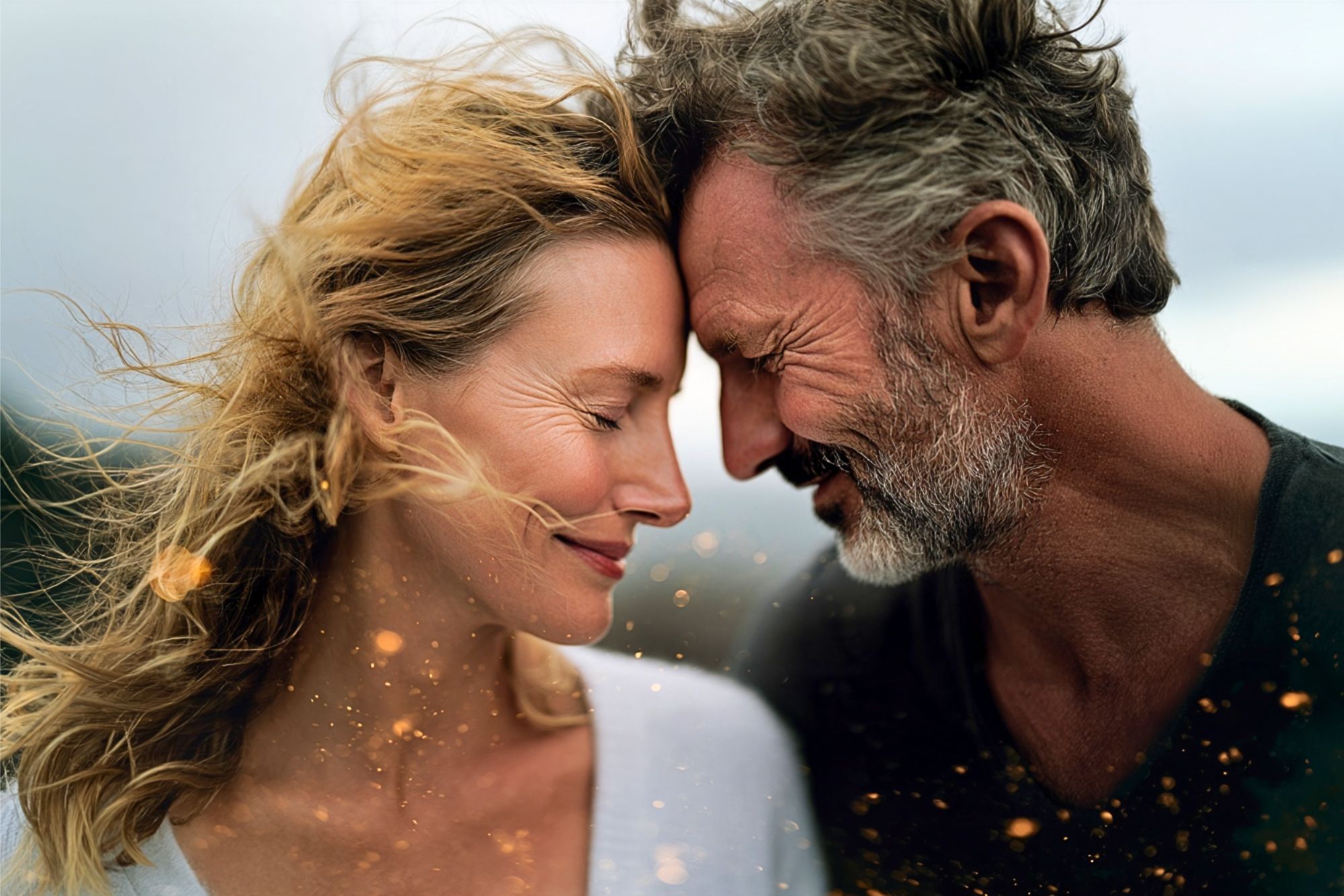 A middle-aged couple leaning toward each other with their foreheads touching and eyes closed.