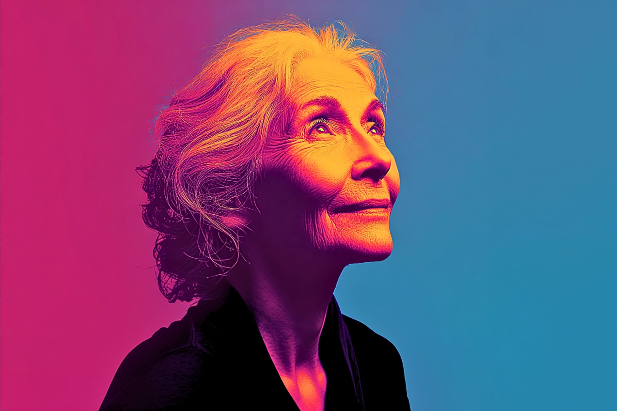 Elderly woman with gray hair looks upward, softly smiling. Image uses dramatic pink, orange, and blue lighting on a plain background, creating a vibrant, artistic effect.