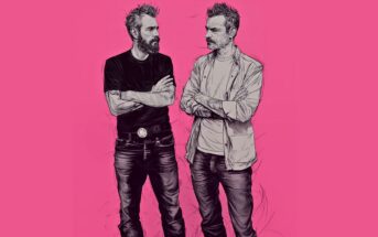 Two men with beards stand facing each other, arms crossed. One wears a black t-shirt and jeans, the other a light shirt over a t-shirt and jeans. The background is solid pink. The style is hand-drawn and sketch-like.