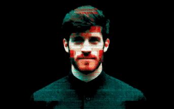 A stylized, pixelated portrait of a man with dark hair and a beard, facing forward against a black background. Red and blue digital glitch effects appear on his face and clothes.