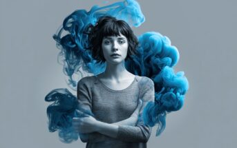 A woman with short dark hair and a neutral expression stands with arms crossed; swirling blue smoke surrounds her against a plain gray background.