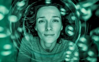 A person with wavy hair gazes calmly upward, surrounded by circular reflections and greenish light, creating a dreamy, underwater-like effect.