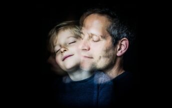 A child and an adult, both with closed eyes and peaceful expressions, overlap in a double exposure effect against a dark background.