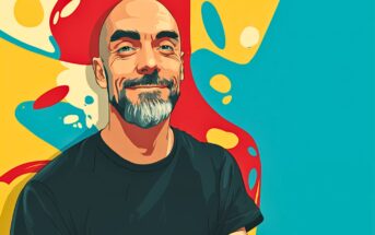 A smiling, bald man with a beard and mustache wears a black t-shirt, standing against a colorful, abstract background with blue, yellow, and red shapes.