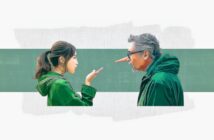 A young woman gestures with her hand toward an older man wearing glasses and a green jacket, who has a long Pinocchio-like nose. Both face each other against a green and white background.