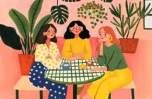 Three women sit around a green-checkered table with drinks, surrounded by large potted plants. They wear colorful clothes and appear to be chatting in a cozy, pink-themed setting.