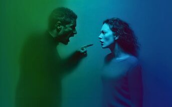 A man with an angry expression shouts and points at a woman who looks shocked. The scene is lit with green and blue light.