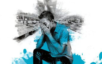 A distressed man sits with his head in his hands in an empty grocery store, surrounded by blue paint splatters and empty shelves, creating a sense of worry and isolation.