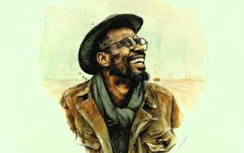 A smiling man with a beard, wearing glasses, a hat, a scarf, and a brown jacket, stands against a light, abstract background.