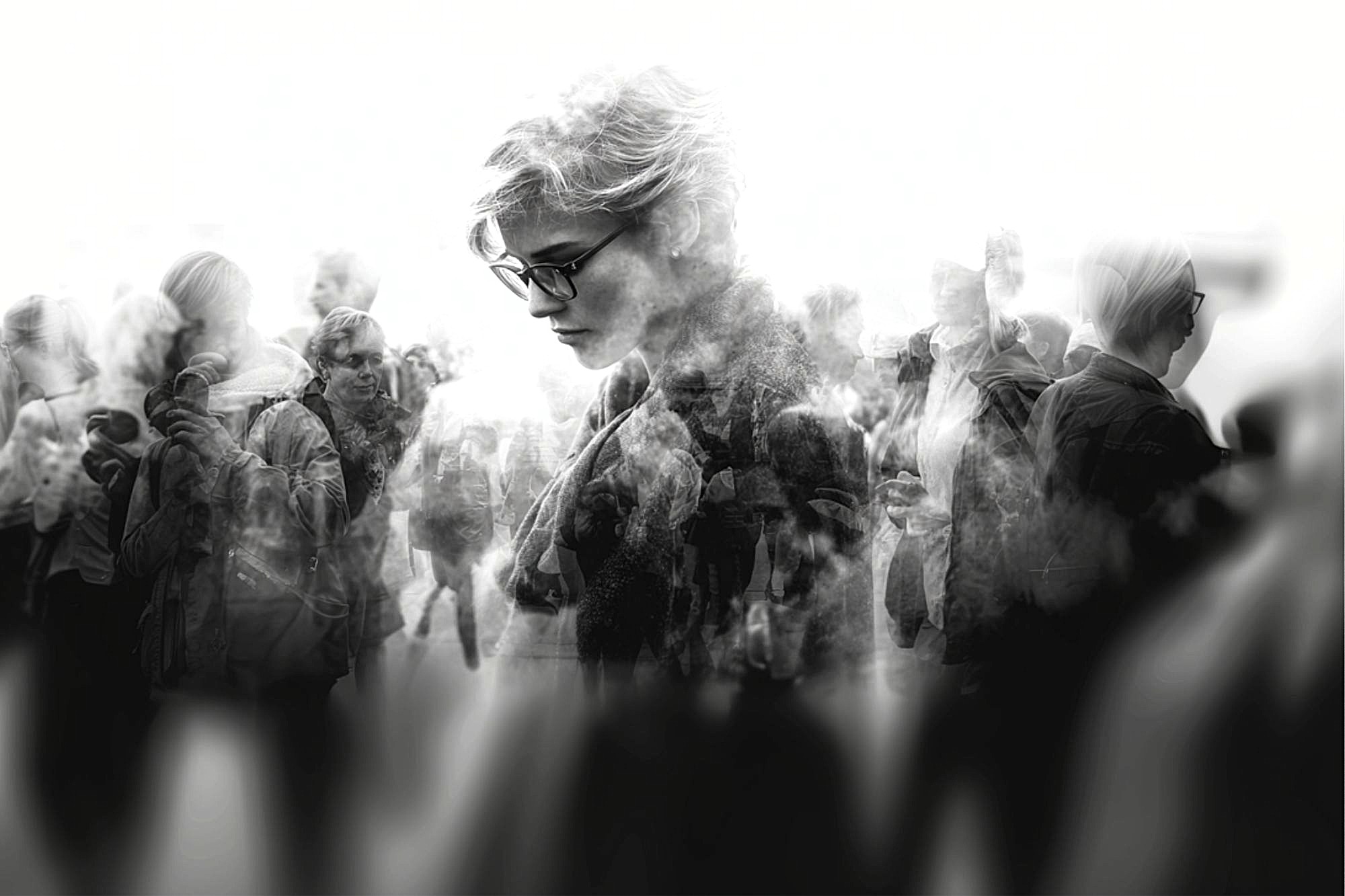 A grayscale image of a person with short hair and glasses, looking downward, is overlaid with multiple blurred silhouettes of people walking in different directions, creating a sense of introspection and crowd.
