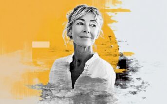 A middle-aged woman with light hair and a slight smile looks off to the side. She wears a white shirt and is set against an abstract background with yellow and gray brush strokes.