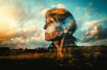 A double exposure image shows an older woman’s thoughtful face blended with a dramatic sky, clouds, and a sunlit field, evoking a sense of reflection and connection with nature.
