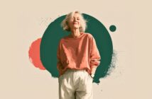 A smiling older woman with short white hair, wearing a loose coral sweatshirt and light pants, stands confidently against a background with abstract green and coral shapes.