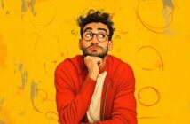 A man with curly hair, a beard, and glasses, wearing a red jacket over a white shirt, rests his chin on his hand and looks upward thoughtfully against a bright yellow background with abstract swirls.