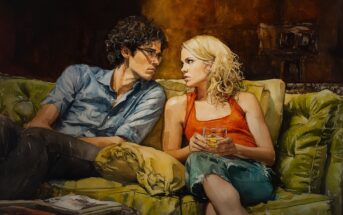 A man and woman sit close together on a green couch, gazing at each other intently. The woman holds a glass, and both appear engaged in a serious conversation in a warmly lit room.