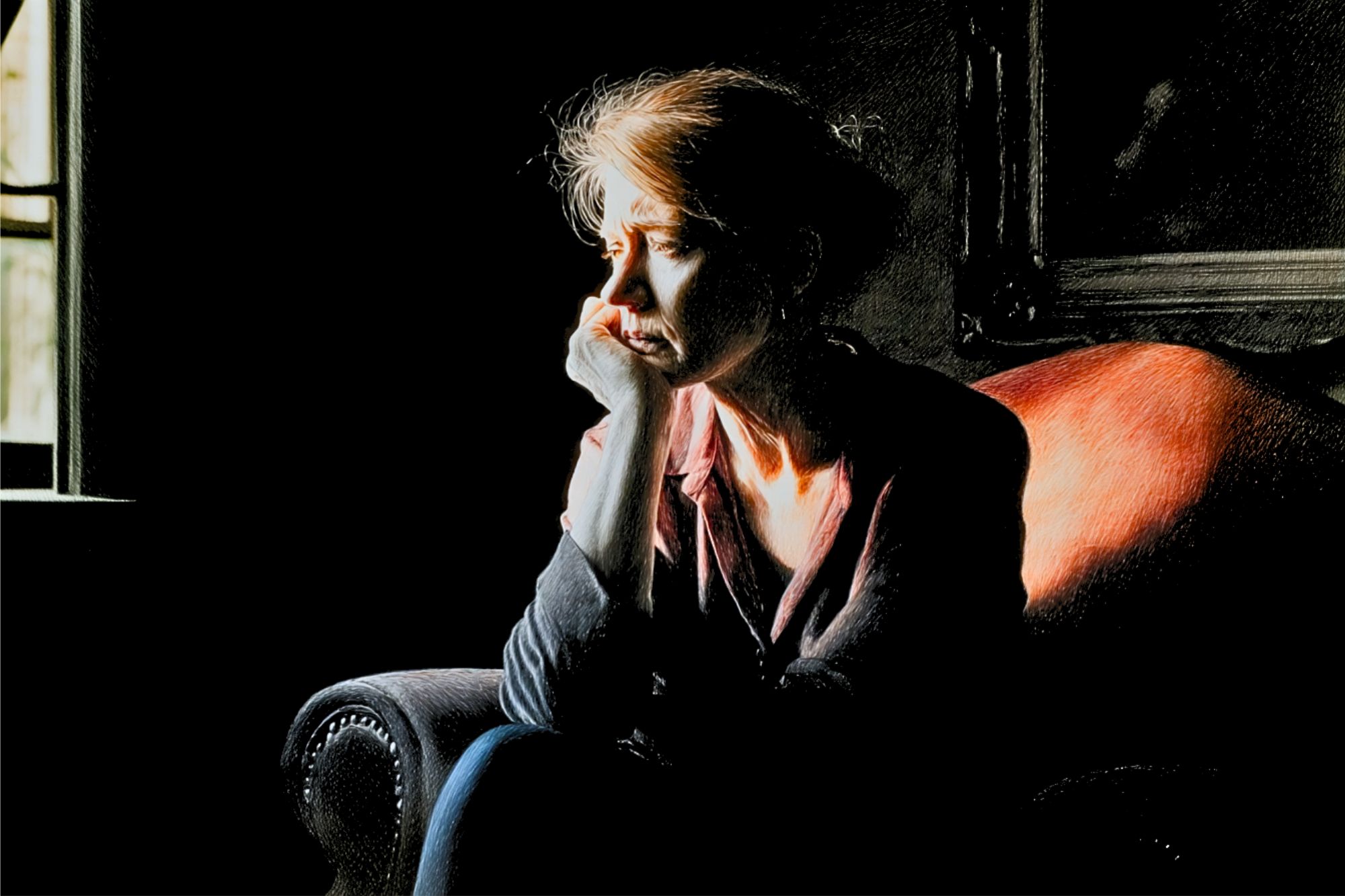 A woman sits alone on a chair in a dimly lit room, resting her head on her hand and gazing out a window, appearing deep in thought.