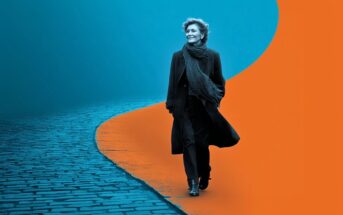 A person in dark clothing walks confidently where a cobblestone path meets a bright orange abstract area, with a blue background creating a striking contrast.
