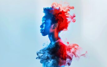 A side profile of a young person with an afro, illuminated by blue and red light. Colorful, smoky clouds in blue and red swirl around and behind their head and shoulders against a pale background.