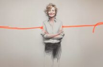 A woman with short, wavy hair stands confidently with arms crossed, smiling. She is sketched in black and white, with a bold orange line running horizontally behind her on a plain background.