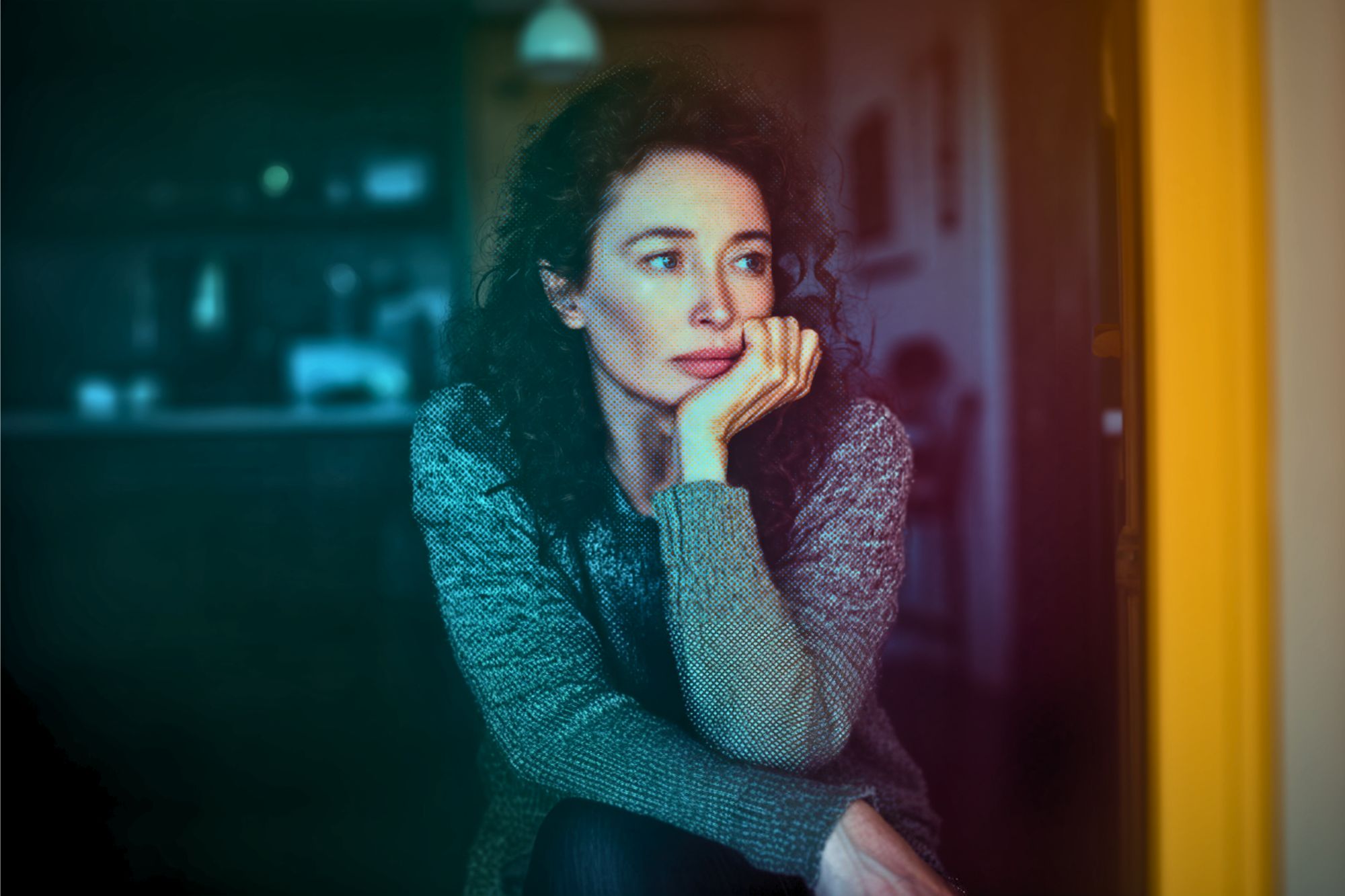 A woman with curly hair and a gray sweater sits indoors, resting her chin on her hand and gazing thoughtfully out of frame. The lighting is soft, with a colorful gradient effect over the image.