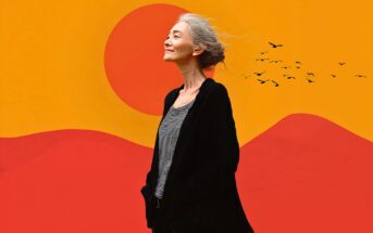 A woman with gray hair stands smiling against a vibrant orange and red abstract background with a large sun and flying birds. She wears a black jacket and striped shirt, hands in her pockets.