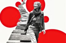 A smiling older woman walks along a winding, broken path. The image is black and white except for large, bold red circles in the background, creating a modern, artistic contrast.