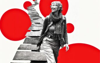 A smiling older woman walks along a winding, broken path. The image is black and white except for large, bold red circles in the background, creating a modern, artistic contrast.