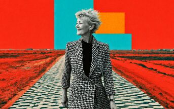 An older woman in a black-and-white houndstooth coat stands on a patterned path in a surreal, vividly colored landscape with bold red ground and geometric shapes in blue and yellow against a red sky.
