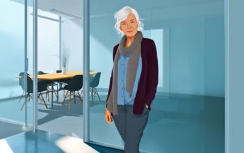 An older woman with white hair, wearing a scarf, cardigan, and blouse, stands smiling in front of a glass-walled office conference room with a table and chairs.