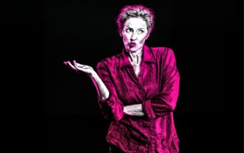 A stylized image of a person with short, curly hair wearing a bright pink shirt, raising one hand and shrugging with a puzzled or uncertain expression against a black background.