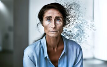 A woman in a blue shirt stares ahead as the right side of her face and hair dissolve into abstract particles, blending with a blurred indoor background.