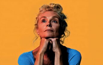 An older woman with blonde hair in an updo gazes upward, resting her chin on her hands. She wears a blue top and is set against a solid orange background. The image has a stylized, high-contrast artistic effect.