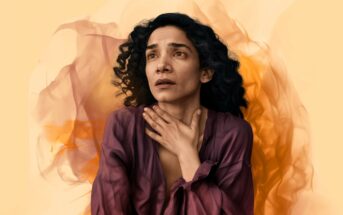 A woman with curly hair wearing a purple top holds her hand to her throat and looks upward with a worried expression, against an abstract orange and yellow background.
