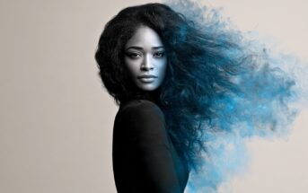 A person with long dark hair that appears to be dissolving into a cloud of blue smoke on one side.
